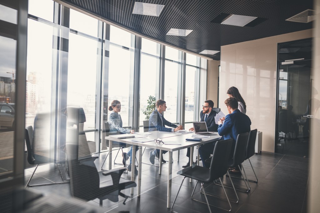 A group of executives in a meeting in a glass office